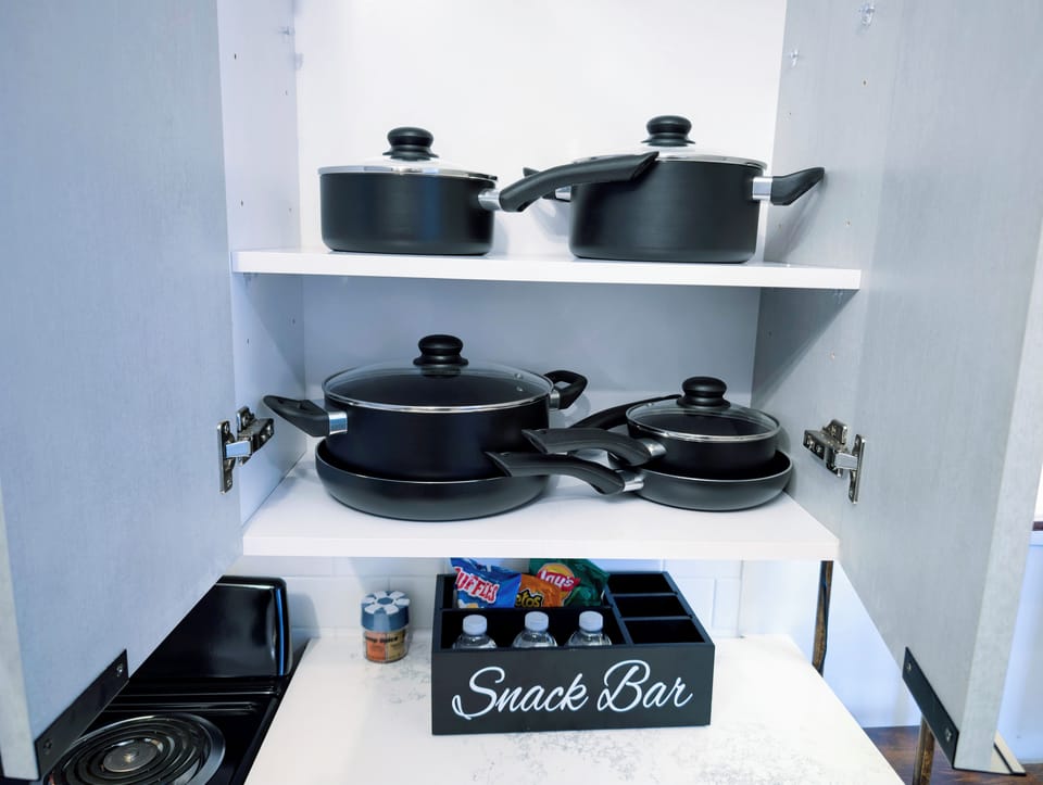 Well-stocked kitchen cabinet with cookware and a welcoming snack bar
