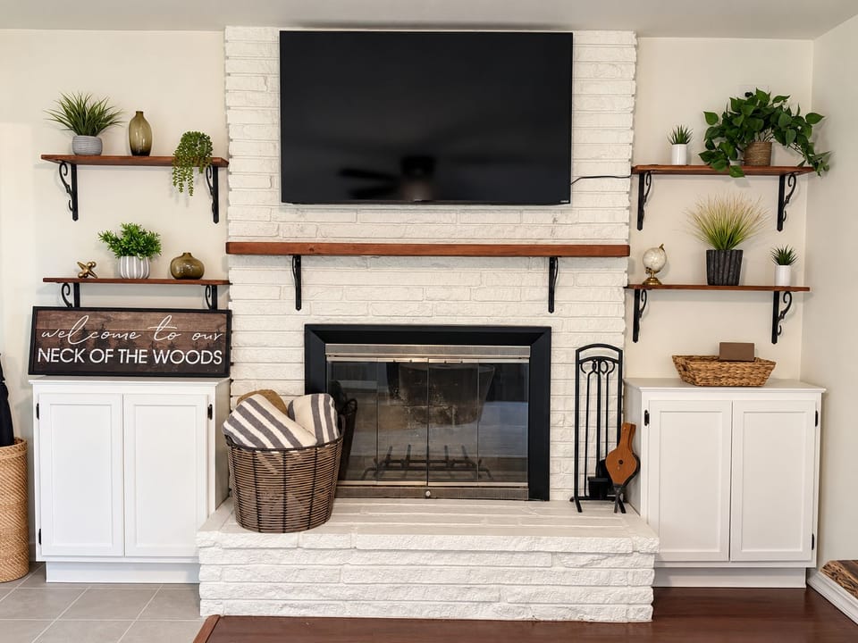Cozy white brick fireplace with TV, stylish shelves, and built-in storage