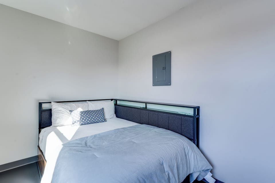 Cozy minimalist bedroom with full bed, modern headboard, and sunlight