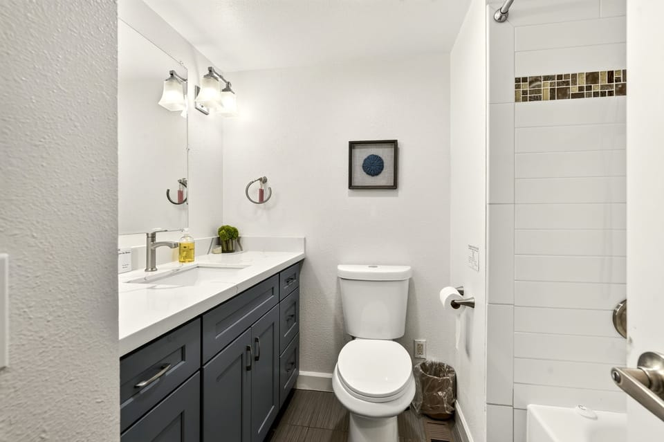 Bright modern bathroom with sleek vanity and tiled shower-tub combo