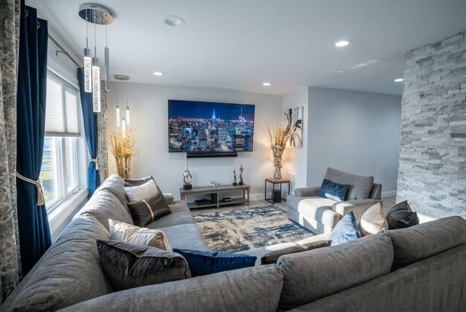 Modern living room with plush seating, big TV, and elegant natural light