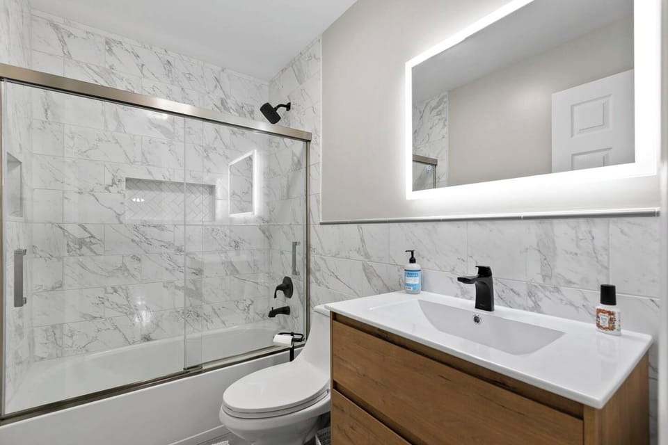 Our upstairs bathroom is inspired by hotel decor, with a floating vanity, lit mirror, and marble tiles. This is where you’ll find the hairdryer.