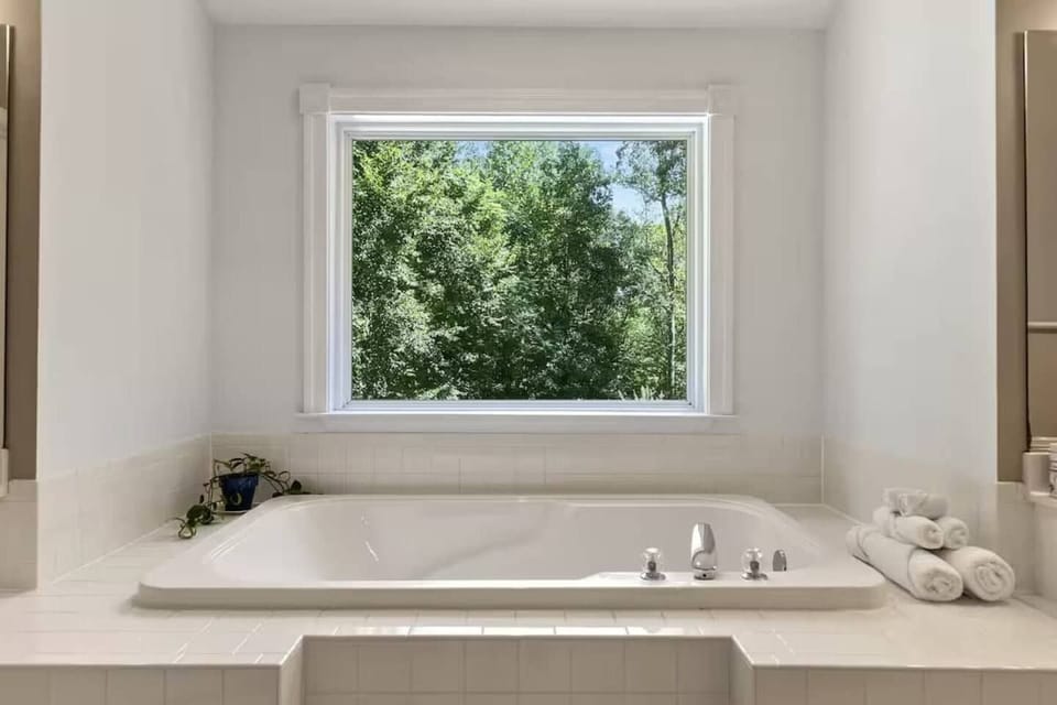 Bright soaking tub with peaceful tree views and spa-like bathroom charm