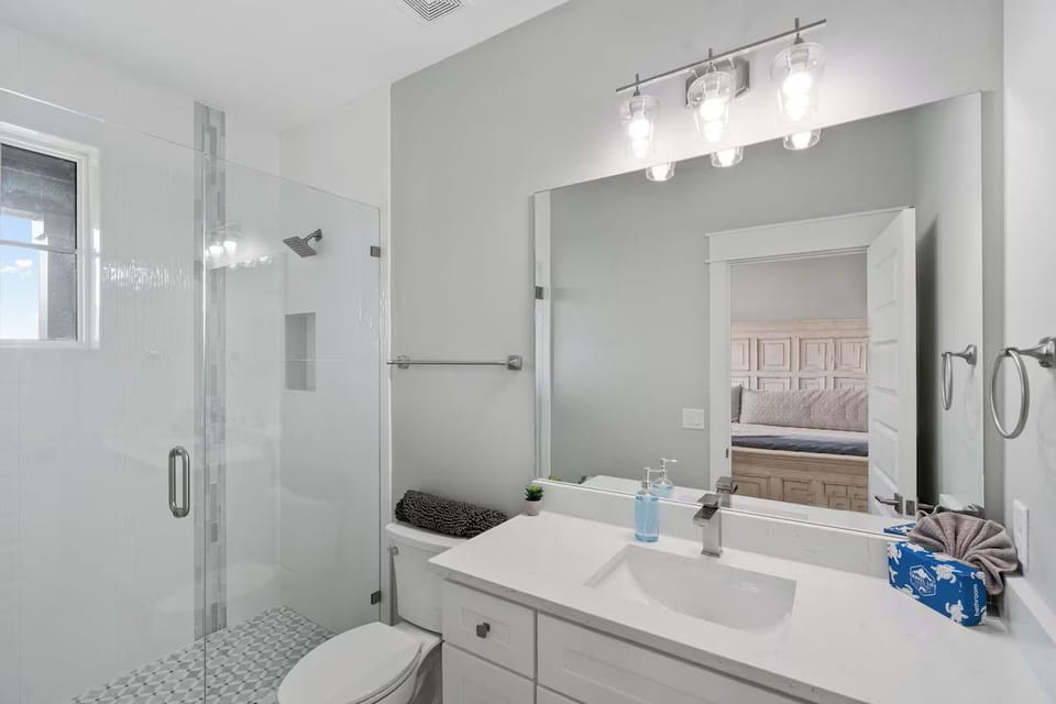 Second Floor King Ensuite: Refresh in this pristine upper-level bathroom, featuring a sleek glassed-in walk-in shower, bright vanity mirror, and fresh fixtures.