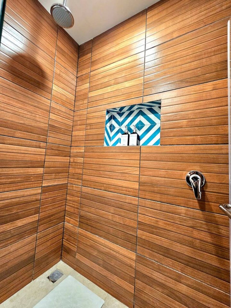 Modern shower area with wood-style wall tiles, a rainfall showerhead and contemporary fixtures.