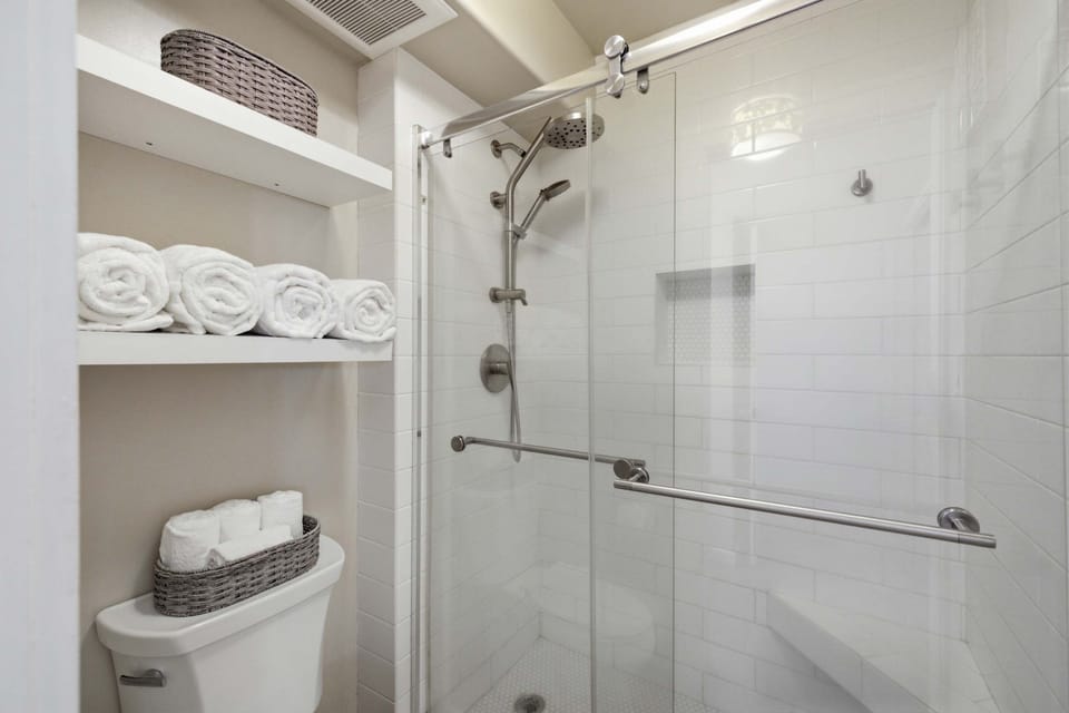 Bathroom with a tiled walk-in shower and convenient built-in storage.