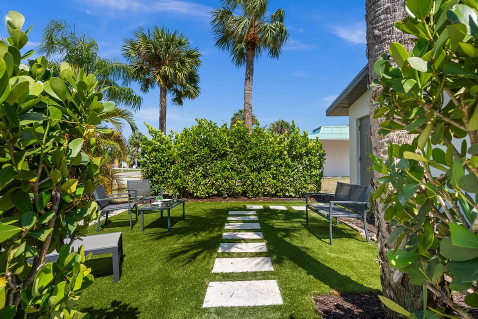 A sunny garden entry welcomes you with tropical greenery, outdoor seating, and a relaxed private courtyard feel.