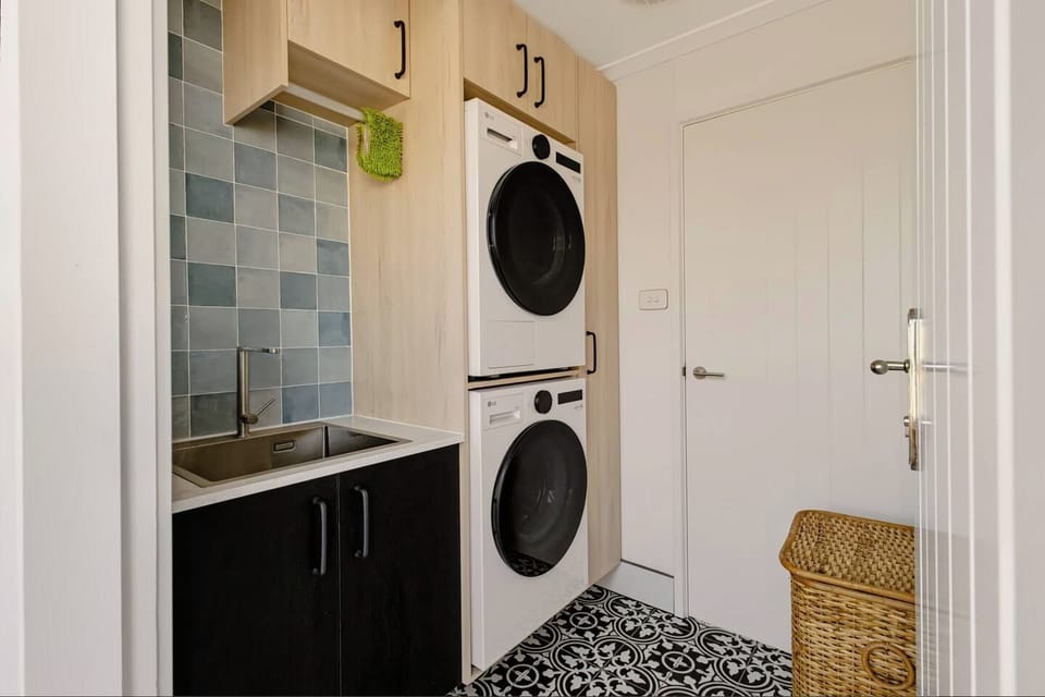 Stacked washer & dryer with laundry sink, iron and ironing board, cordless vacuum, and detergent provided. Direct outdoor access door for fresh air flow or quick trips outside  — practical and comfortable for family stays.