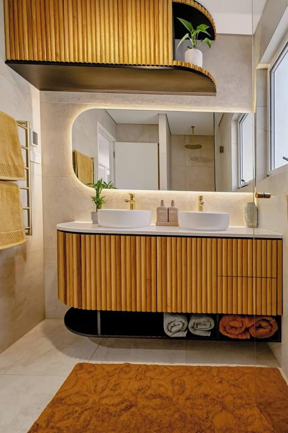 Designer bathroom with double vanity, gold accents, and spa-style finishes