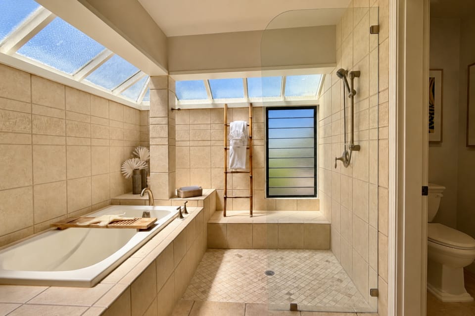 Your bathroom's large soaking tub and glass-enclosed shower share a bright corner, with a towel ladder and toilet room tucked to the side. KBV-16B3