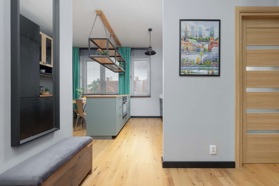 The entryway hallway is bright and inviting, leading smoothly towards the main living areas. A large mirror and a dark green seating bench offer practical convenience right near the door.