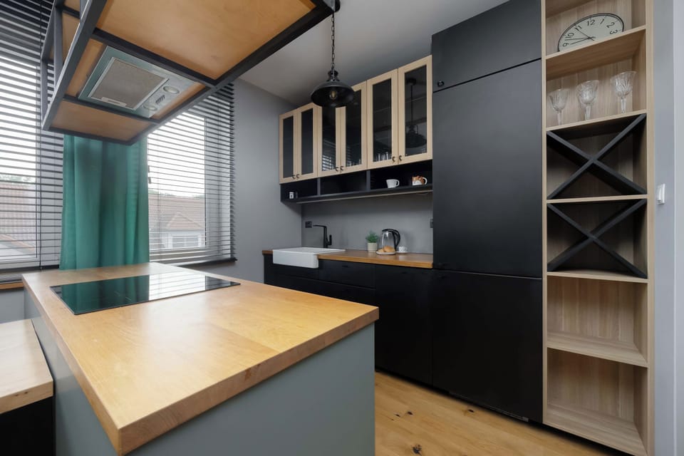 A detailed look at the kitchenette's workspace, featuring a large, functional wooden peninsula. Open shelving with built-in wine racks adds both utility and visual interest to the cooking area.