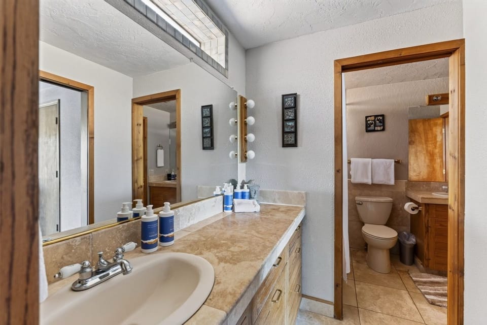 Your private bathroom features dual vanities and thoughtful lighting, giving you plenty of space to refresh. The separate toilet area adds a touch of privacy during your stay.