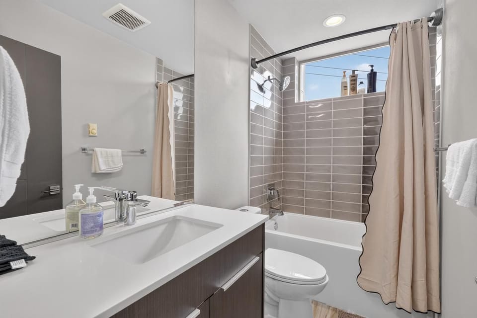 Bright modern bathroom with sleek vanity and tiled shower-tub combo