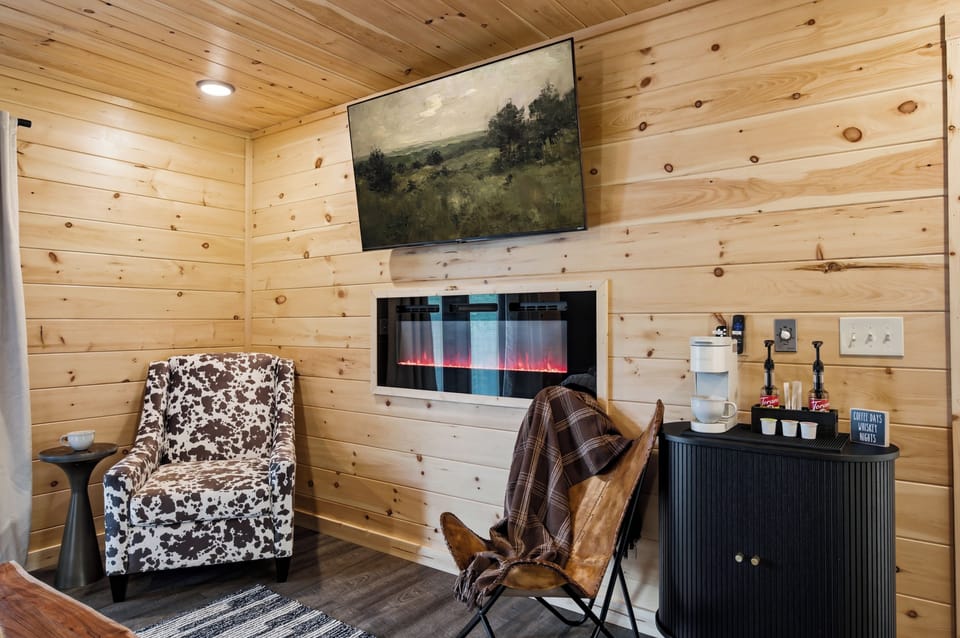 Cozy wood-paneled lounge with fireplace, TV, and in-room coffee station