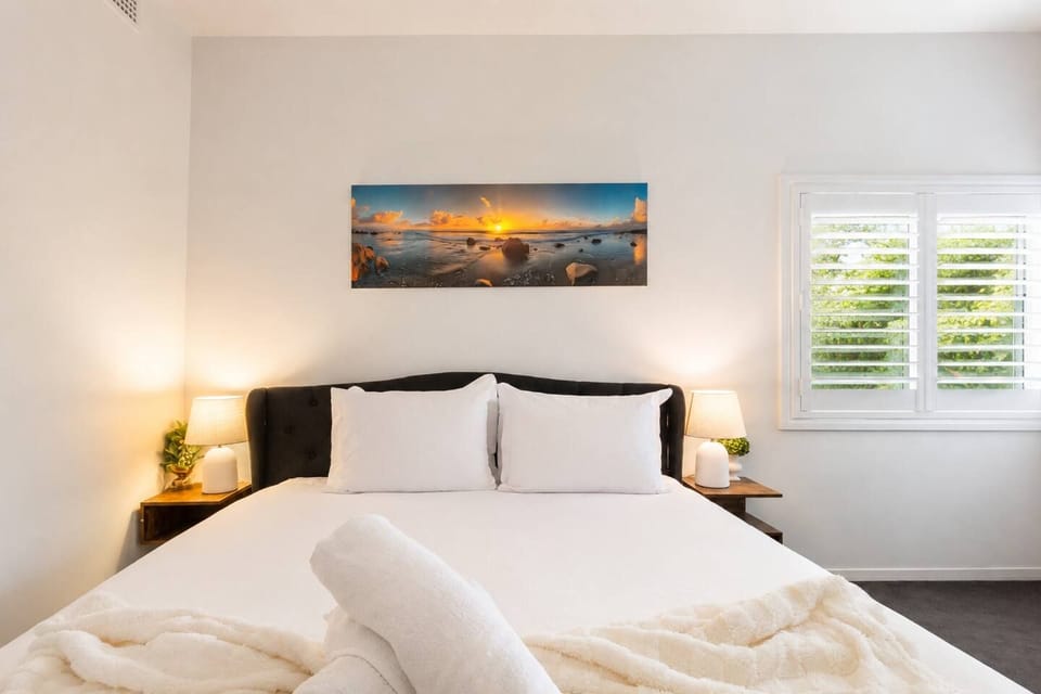 Bright, cozy bedroom with crisp linens, warm lighting, and serene artwork