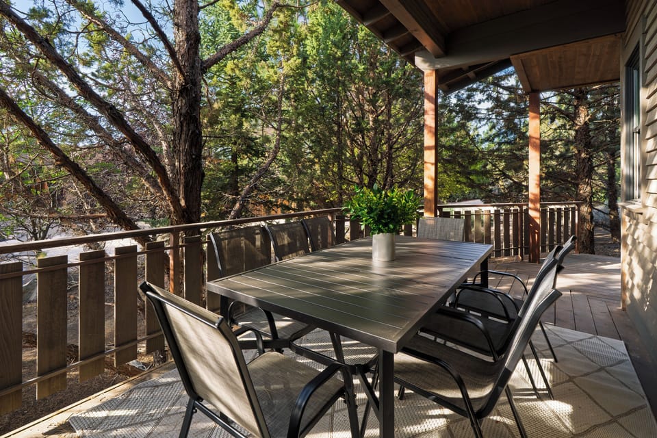 Covered deck with outdoor dining surrounded by trees.