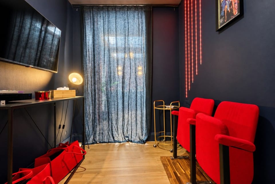 Salon — fauteuils de cinéma, télévision murale et grande fenêtre voilée