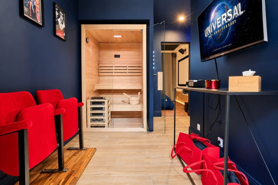Salon cinéma — fauteuils rouges, télévision et sauna vitré