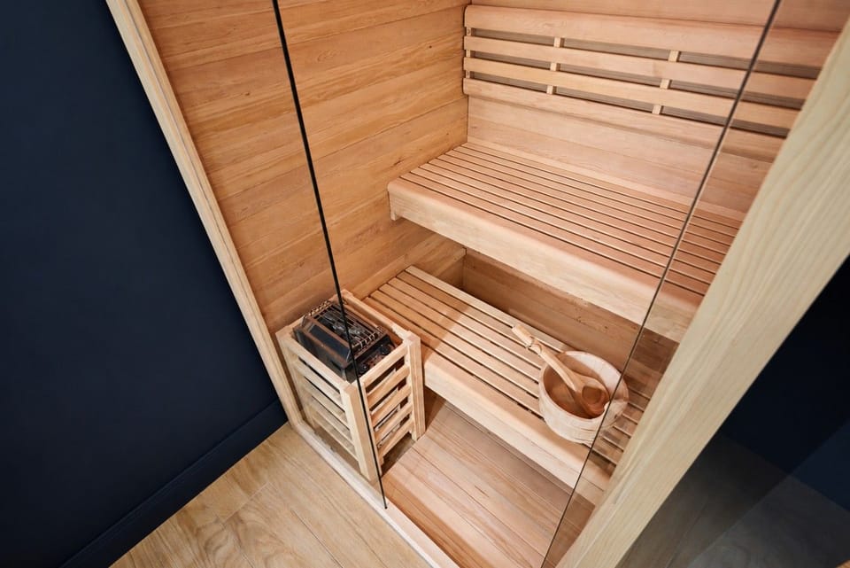 Sauna — bancs en bois, poêle, seau et louche