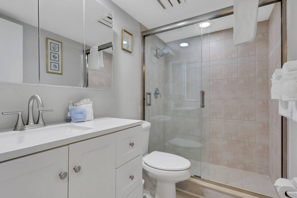 The updated guest bathroom features a spacious vanity and glass-enclosed walk-in shower.