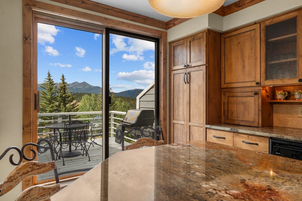 Enjoy your morning coffee at the granite island while taking in stunning mountain vistas through floor-to-ceiling windows that open to your private deck with outdoor dining and BBQ.