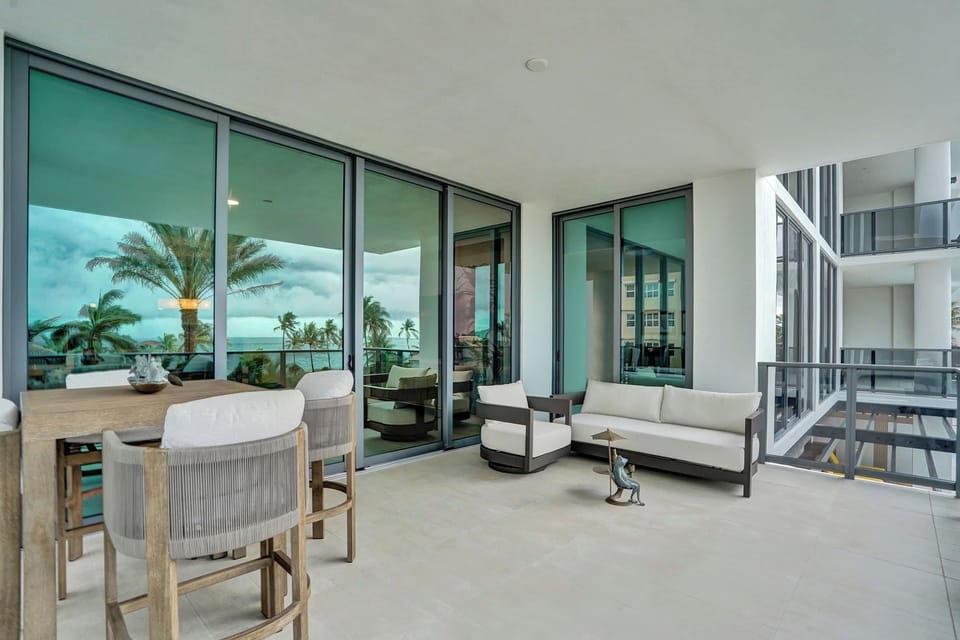 Wraparound balcony with bar seating and lounge chairs framed by floor-to-ceiling glass.