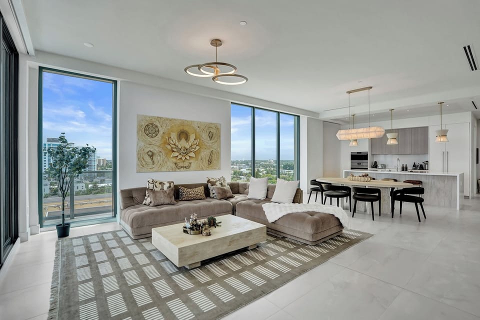 Open-plan living and dining with floor-to-ceiling windows and panoramic city and ocean views.