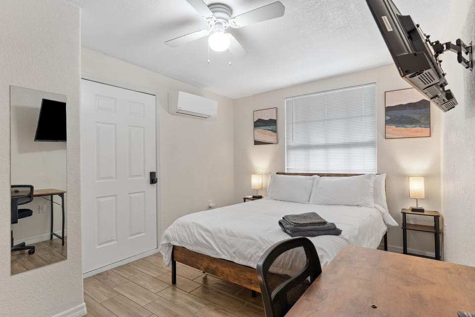 Your bright, modern bedroom invites you to unwind with crisp white linens, warm bedside lighting, and a ceiling fan to keep you comfortable. Art adorns the walls, and a dedicated workspace lets you stay productive when needed.
