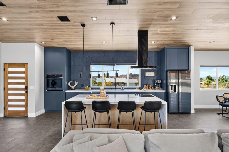 Sleek kitchen with bold blue cabinetry, an oversized island, and desert views from the window.