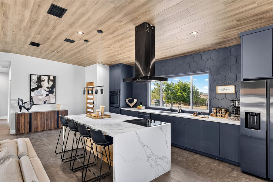 Showpiece kitchen with a waterfall island, black hex tile backsplash, and a dedicated coffee station.