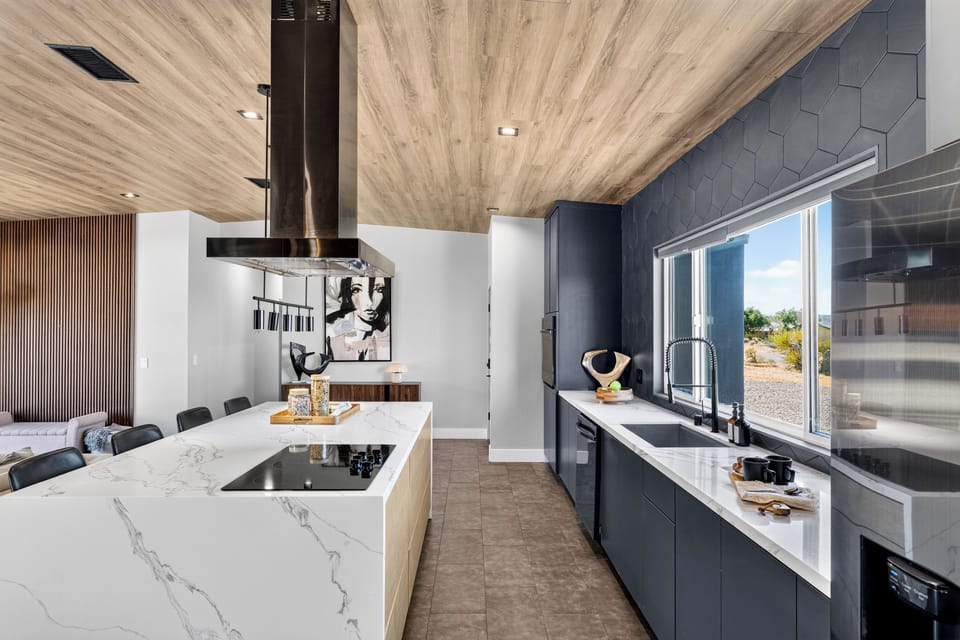Showpiece kitchen with a waterfall island, black hex tile backsplash, and a dedicated coffee station.