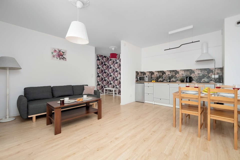 The living room is decorated in a modern, minimalist style with bright white walls and light wooden flooring.