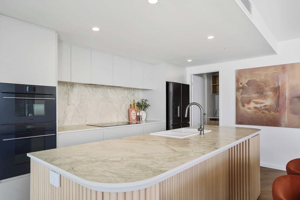 Bright modern kitchen featuring sleek white countertops and stone accents.