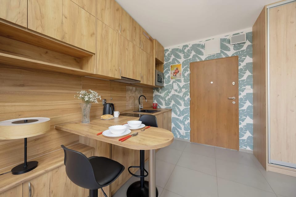 A compact dining area with a round table and two bar stools next to the kitchenette. The wooden cabinetry offers plenty of storage and complements the warm interior.