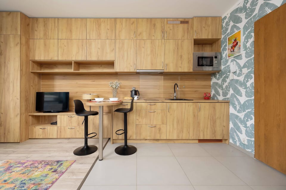 A well-equipped kitchenette with wooden cabinets, a countertop, and a small dining table. Two bar stools create a convenient spot for enjoying meals.