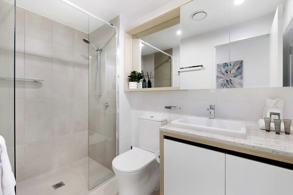 Refresh in a bright, modern bathroom featuring a floating vanity, vessel sink, walk-in glass shower, and large mirror