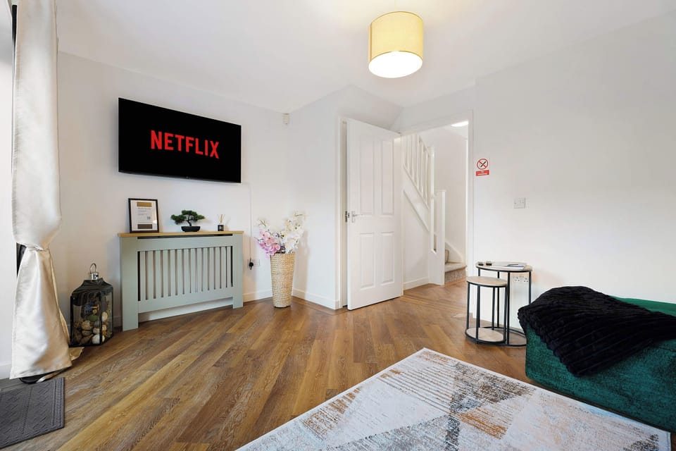 Relax in style within this bright living space, featuring rich wooden flooring and contemporary decor. Highlighted by a modern media screen and abundant natural light from glass patio doors, this sophisticated room offers the environment to unwind.