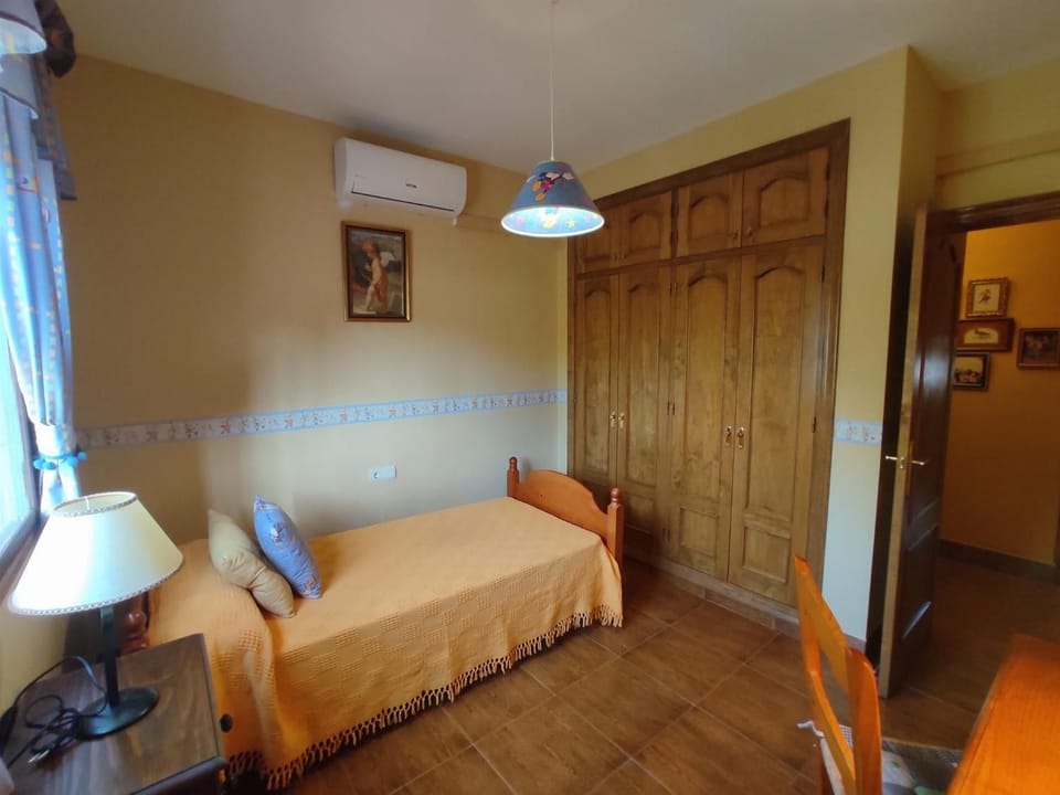Traditional family bathroom inside a rustic holiday villa, featuring diamond-patterned wall tiles, a marble-top vanity sink, a standard toilet and bidet, and a full bathtub with a bright yellow shower curtain.