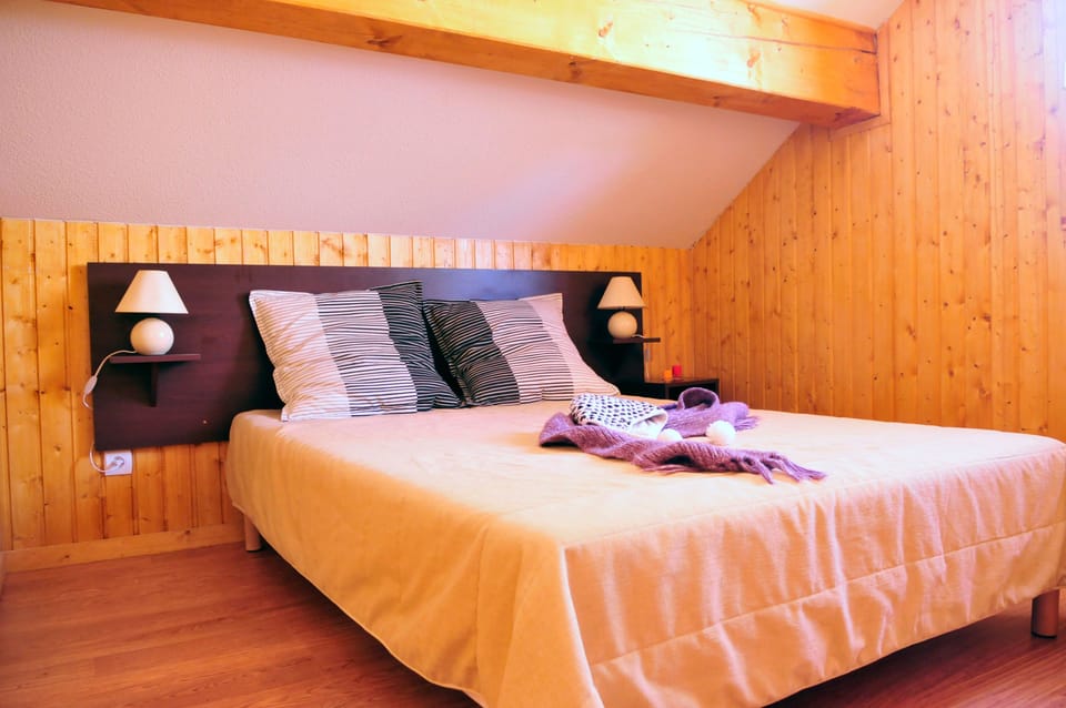 Unit bedroom, double bed, wood-paneled attic ceiling.