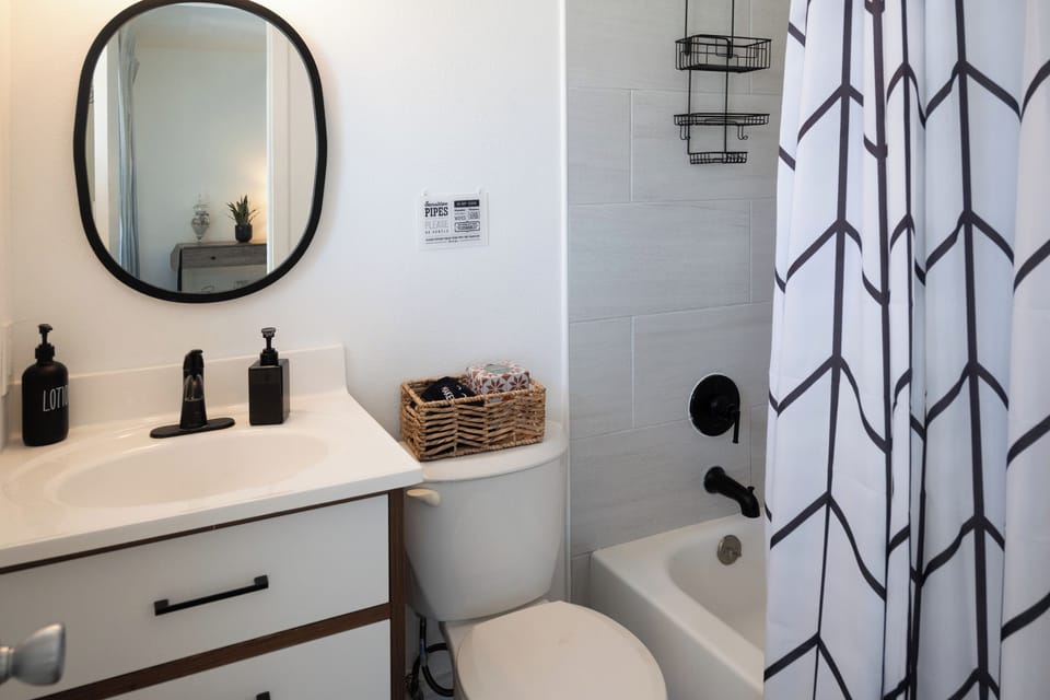 Coral House 1BR – Bathroom with tub/shower combo, vanity and hotel-style toiletries