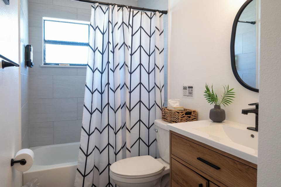 Coral House 2BR – Bathroom with tub/shower combo, modern vanity and hotel-style toiletries