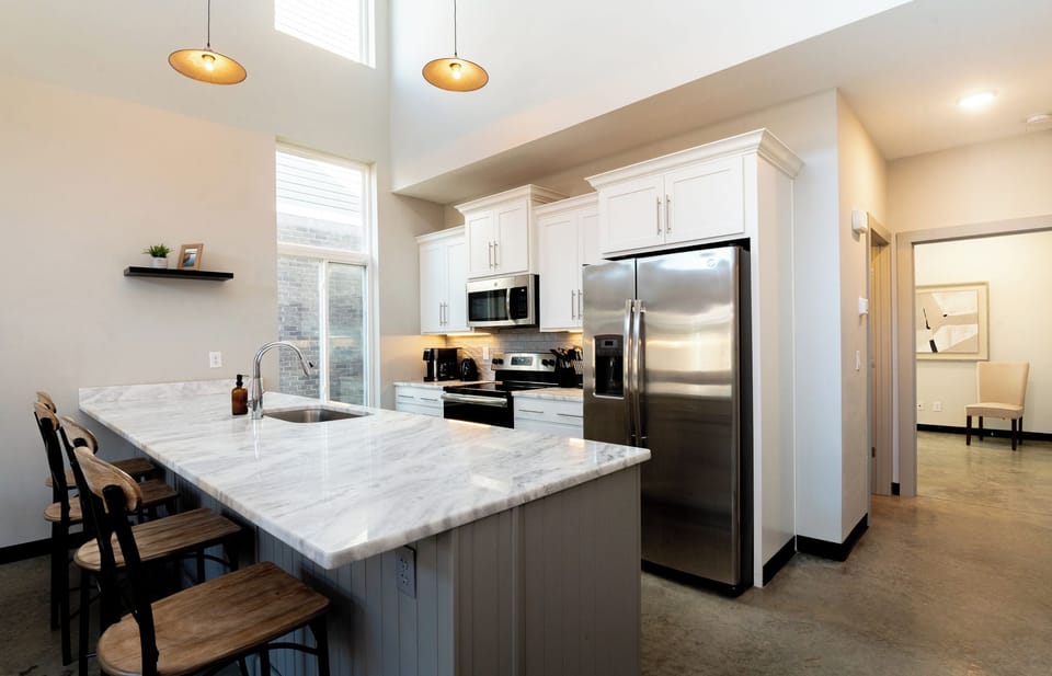 Prepping a quick snack is an absolute joy on these expansive white marble counters. Those dark wooden barstools provide the perfect spot to sip a glass of wine.