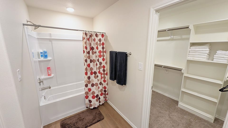 Bright bathroom with tub-shower combo and spacious walk-in closet