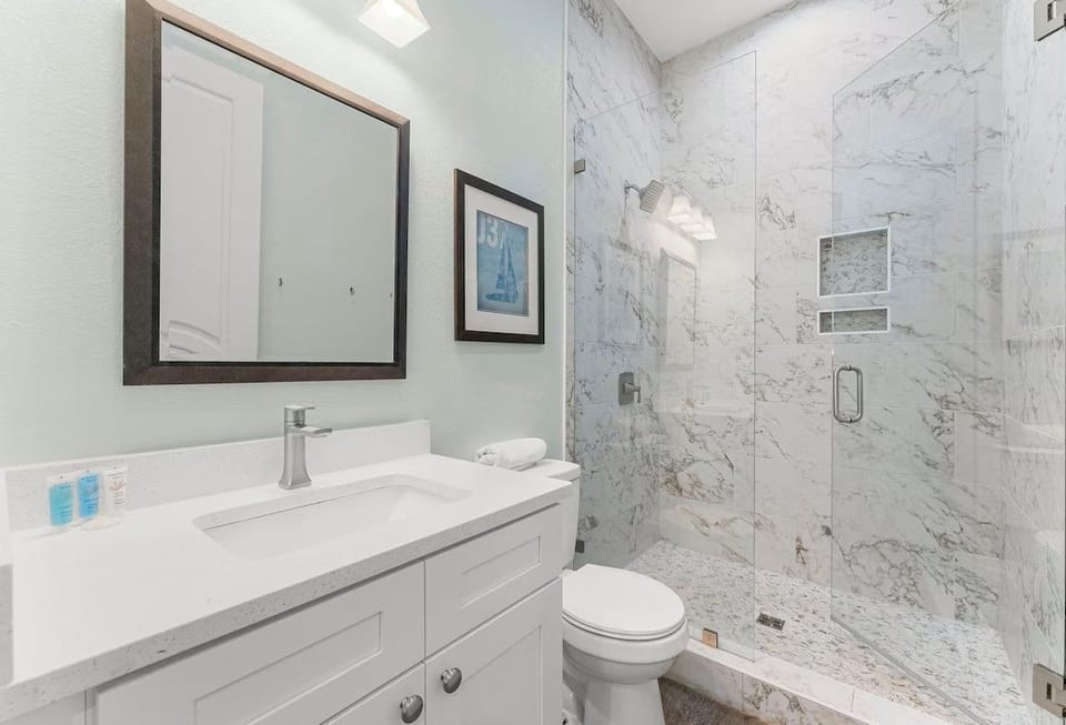 Luxurious 1st floor en-suite bathroom featuring a modern glass-walk-in shower, sleek vanity, and pristine finishes.