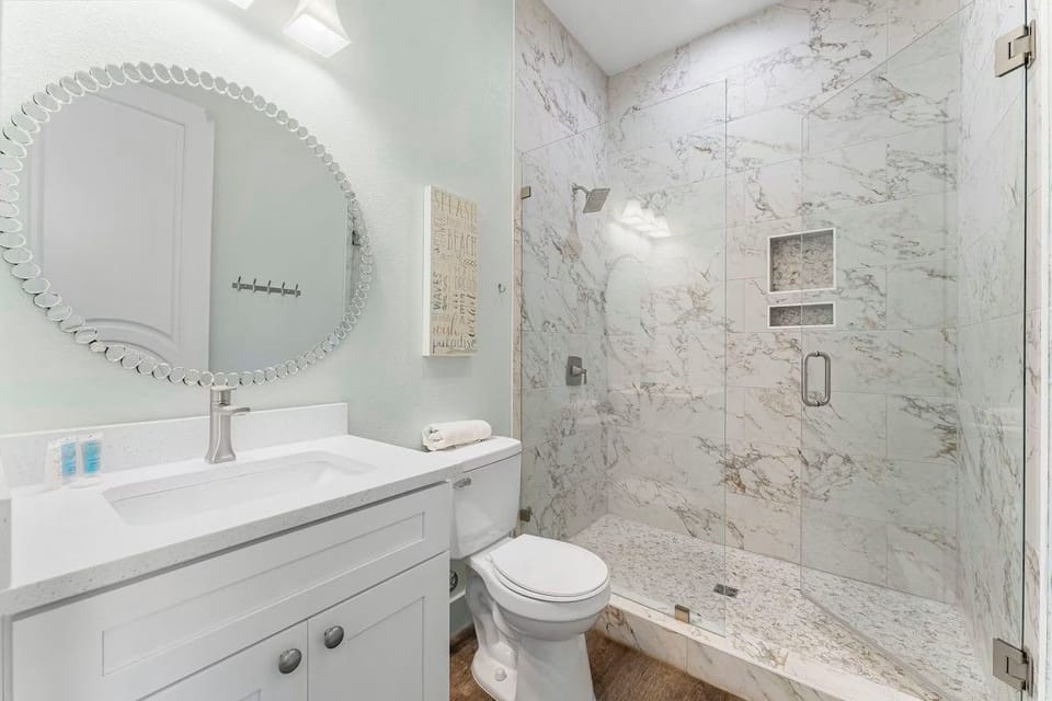 This sparkling 1st floor en-suite bathroom offers a contemporary walk-in shower with designer tile and a well-lit modern vanity mirror.