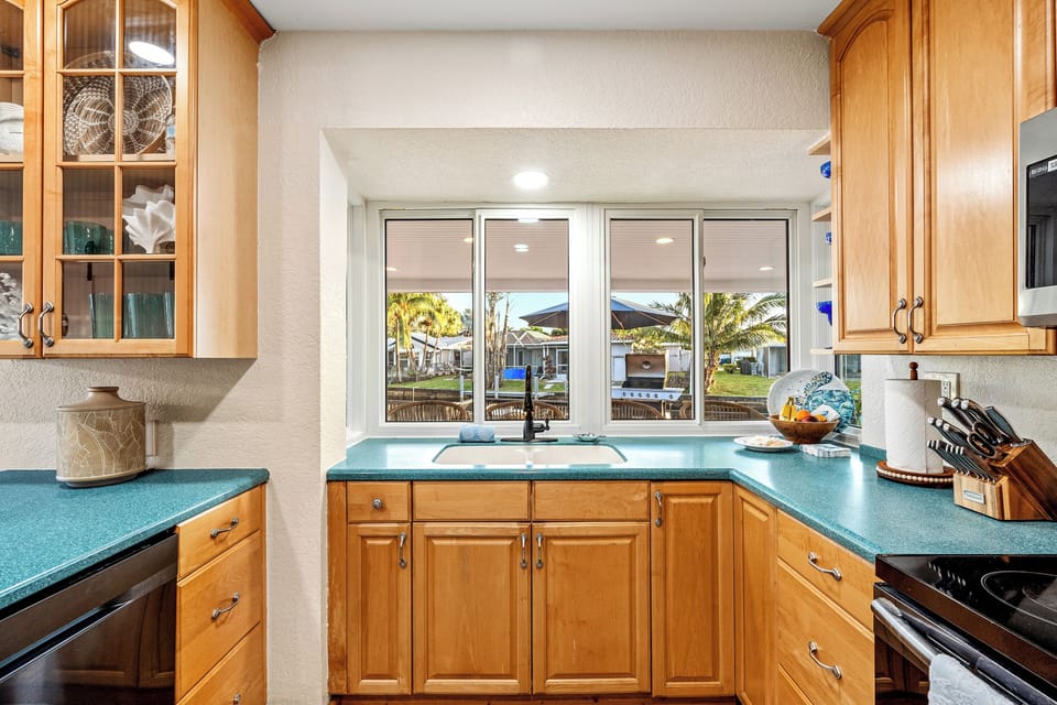Bright kitchen with backyard views, ample counters, and warm wood cabinetry
