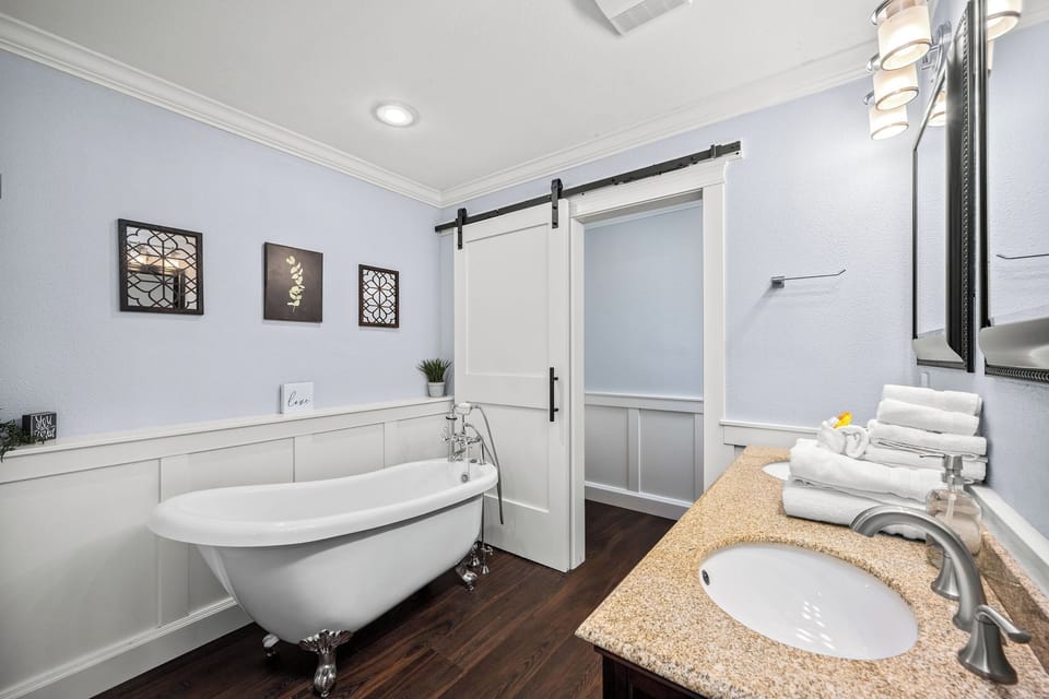 Soak your worries away in this elegant clawfoot tub, surrounded by soothing blue-gray walls and charming farmhouse touches that make every bath feel like a spa retreat.
