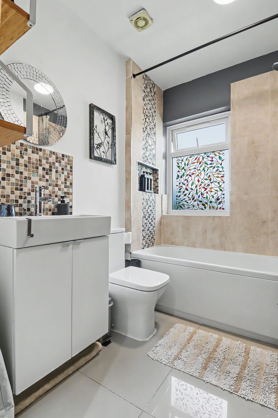 Bright modern bathroom with full tub, stylish tile accents, and natural light