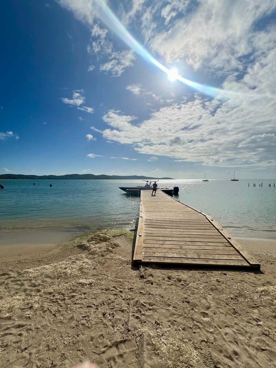 Wooden dock stretching out to calm, crystal-clear waters on a sunny day